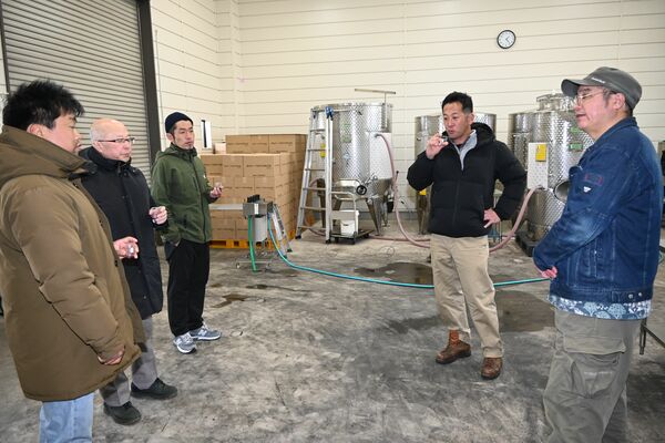 醸造所施設でワイン醸造について製造担当の荒井誠之さん（右）から取り組みを聞く一行＝２月８日、鹿沼市下奈良部町