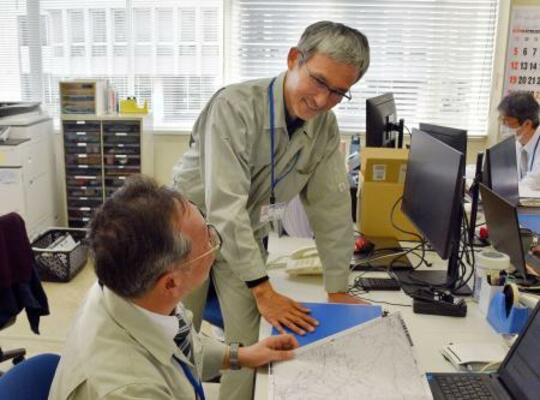 石川県珠洲市役所で業務主任の門前修さん(手前)と話す熊本市職員の後藤升郎さん=14日