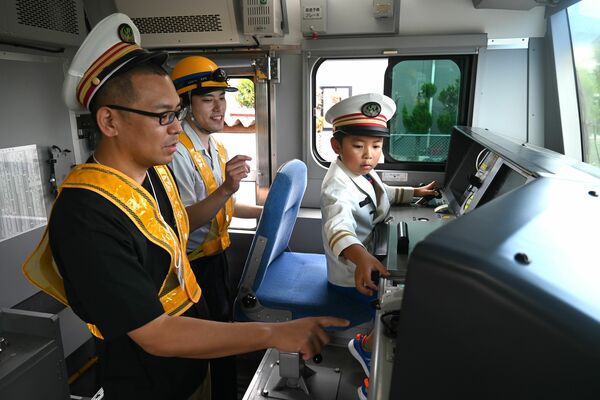 本物の電車の運転席機器を操作する安達さん親子