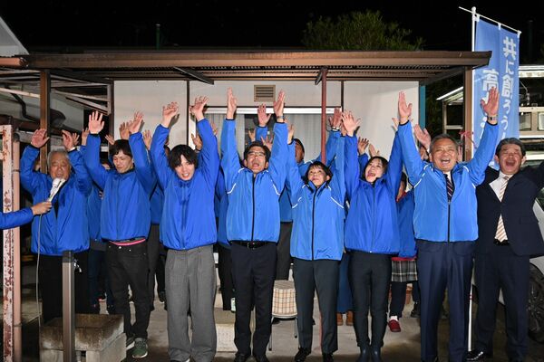 初当選を果たし、万歳する神林秀治氏（中央）＝13日午後９時１０分、高根沢町宝積寺 