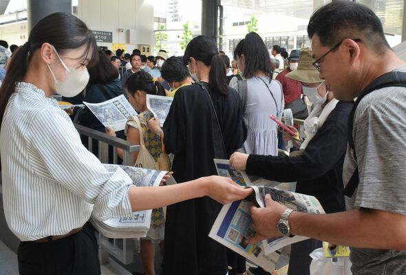 下野新聞の号外を受け取る人たち＝26日午後２時50分、宇都宮市宮みらい