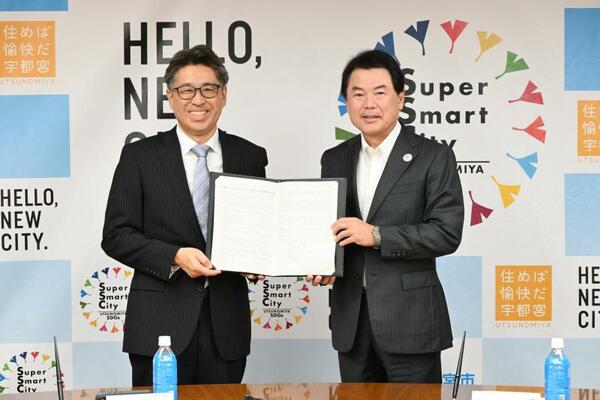 協定書を手にするヤマゼンコミュニケイションズの山本社長(左)と佐藤市長