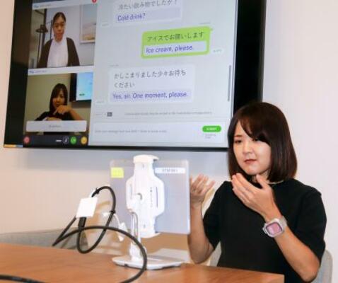 　タブレットに向かって手話で話しかけるソフトバンク社員＝２５日、東京都港区