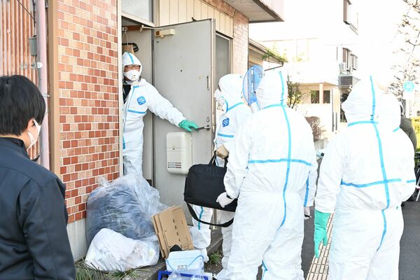防護服を着て家宅捜索に入る捜査員＝15日午前10時20分、足利市内