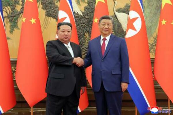 　握手する中国の習近平国家主席（右）と北朝鮮の金正恩朝鮮労働党総書記＝４日、北京（朝鮮中央通信＝共同）