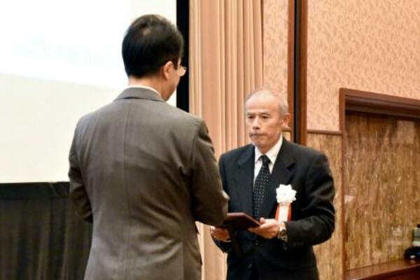 　「地域貢献大賞」の表彰式で日本新聞協会の中村史郎会長（左）から大賞の記念の盾を受け取る北國新聞宝立販売所の船本寛所長＝２０日午後、東京都千代田区