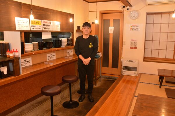 カウンターと小上がりのある店内に立つ板垣代表