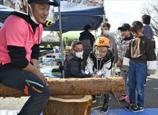 丸太切りを体験する小学生