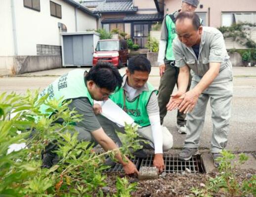 土地家屋調査士と土地の境界を確認する中居正樹さん(右端)=22日午前、石川県内灘町