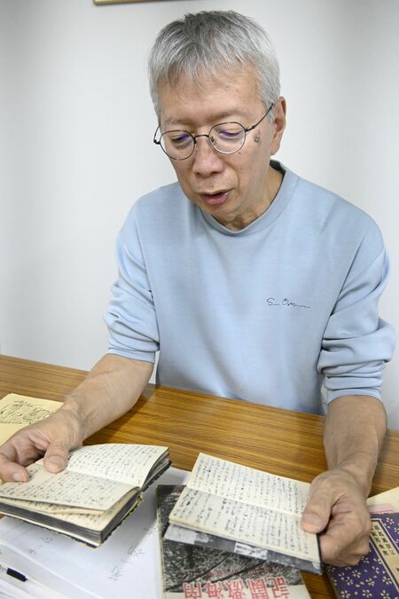 父の兄栄一さんが戦地でしたためた手帳を手に取る昭夫さん＝10月中旬、東京都大田区