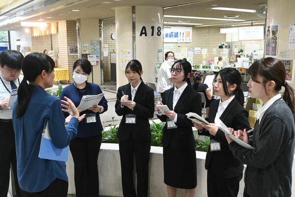 職場見学で職員から説明を聞く参加者ら