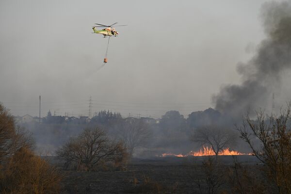 防災ヘリによる消火作業＝18日午後４時15分、小山市