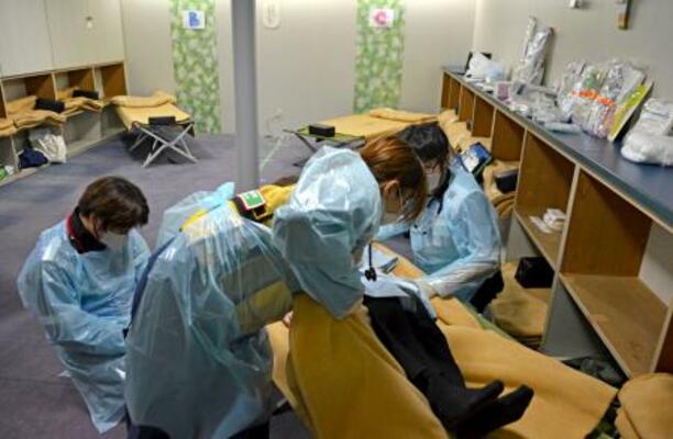 神戸港で行われた「病院船」の活用に向けた訓練で、患者の治療手順を確認する医療関係者ら=16日午後