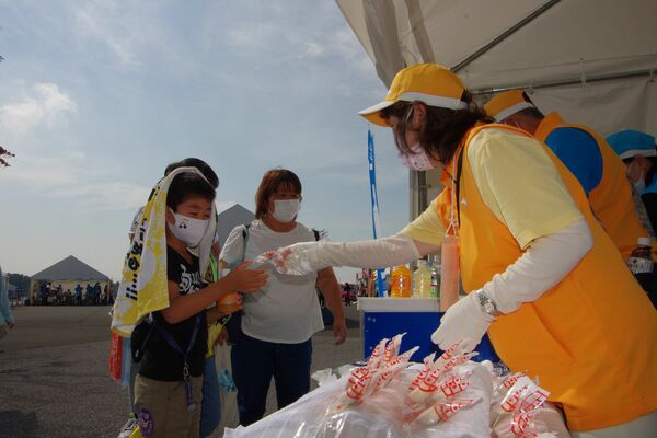 イチゴの菓子を受け取る来場者（左）