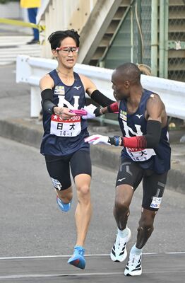 日大１区の山口彰（左）が２区の選手にたすきをつなぐ＝横浜市鶴見区、湯田大士撮影