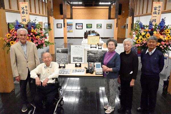 檜山さんの遺影を挟んで立つ田口さん（左から２人目）、鶴見さん（同３人目）、檜山伶子さん（同４人目）ら