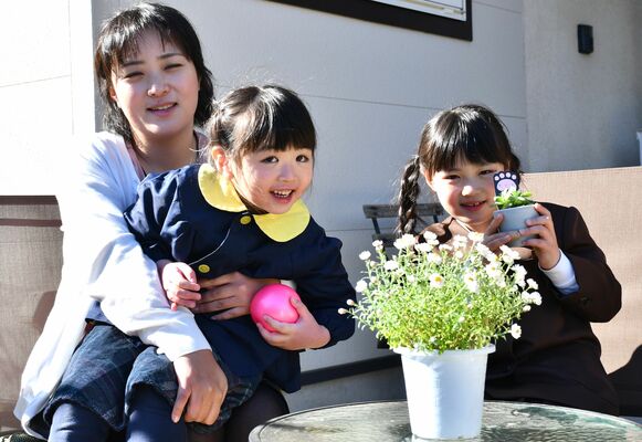石川県内に戻った西本真理さん（左）と長女瑠璃さん（右）、次女瑠那さん（中央）。市内で買ったハナカンザシもそばにある