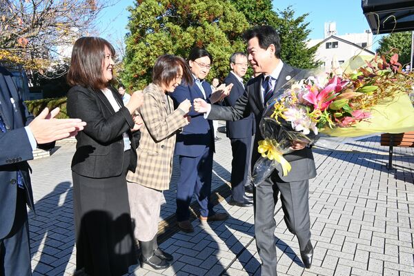 拍手で出迎える職員とグータッチする佐藤市長