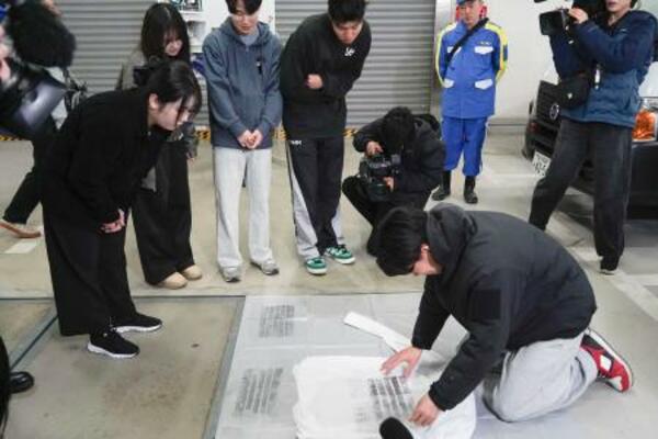 　交通事故捜査を体験する学生ら＝１２日午後、警視庁神田署