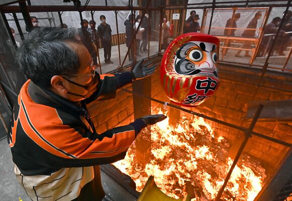 縁起物を炎の中に投げ入れる係員＝15日午後２時15分、宇都宮市馬場通り１丁目
