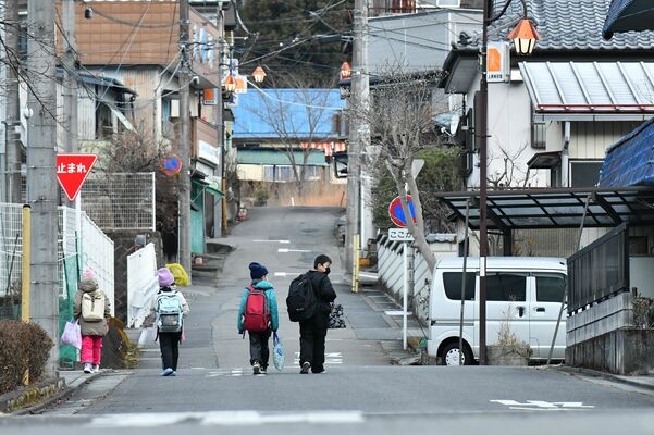 リュックサックを背負い並んで歩く子どもたち。併設となった足尾小中学校には児童生徒40人ほどが通う＝２０２２年12月中旬、日光市足尾町通洞