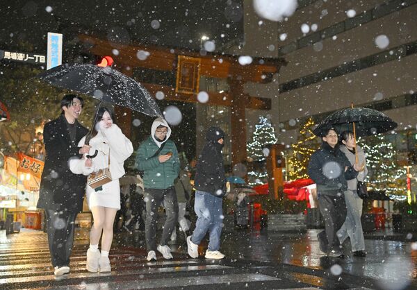 傘を差したり、洋服のフードをかぶったりして雪をよける人たち＝２日午後５時10分、宇都宮市馬場通り１丁目