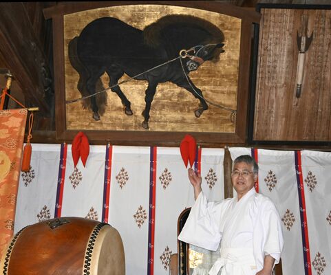 野木神社に伝わる黒馬繋馬図絵馬を示す海老沼宮司