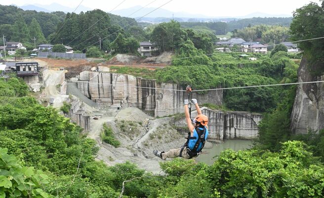 ワイヤにぶら下がって採石場の上を勢いよく降りるジップライン