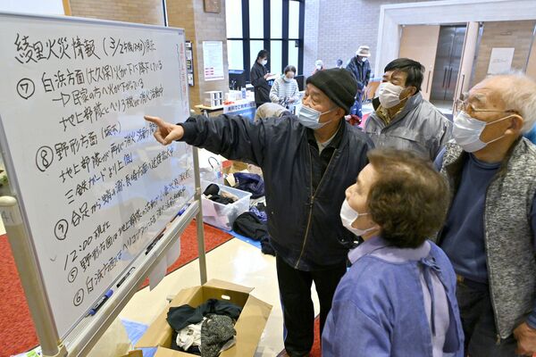 避難所に掲示された火災情報に見入る避難者たち＝２日午後、岩手県大船渡市三陸町越喜来