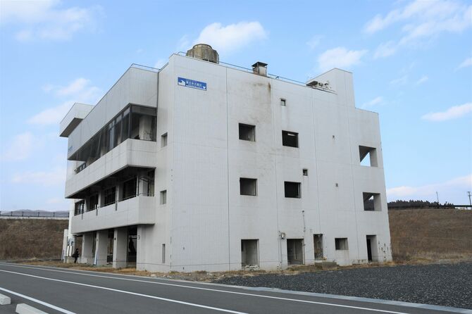 震災遺構として残る高野会館。建物上部の青いマークには「津波浸水深ここまで」と示されている