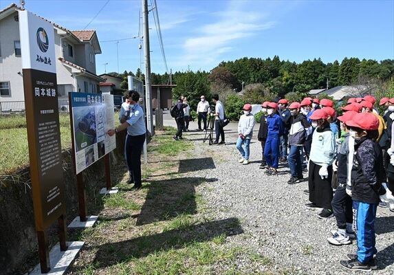設置された看板の前で城跡の説明を聞く児童ら