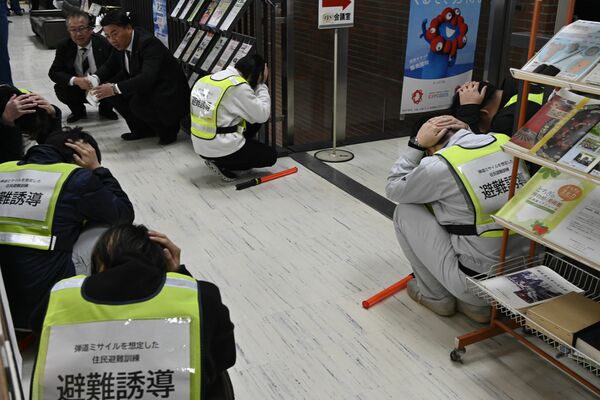 頭を抱えてしゃがみ込む避難誘導役の市職員ら