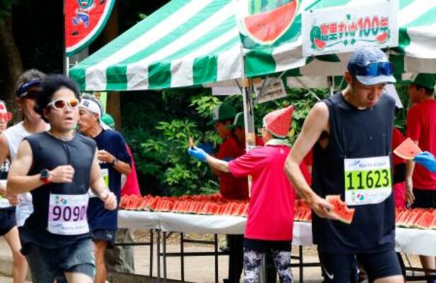 「富里スイカロードレース」で、スイカを食べるランナー=14日午前、千葉県富里市