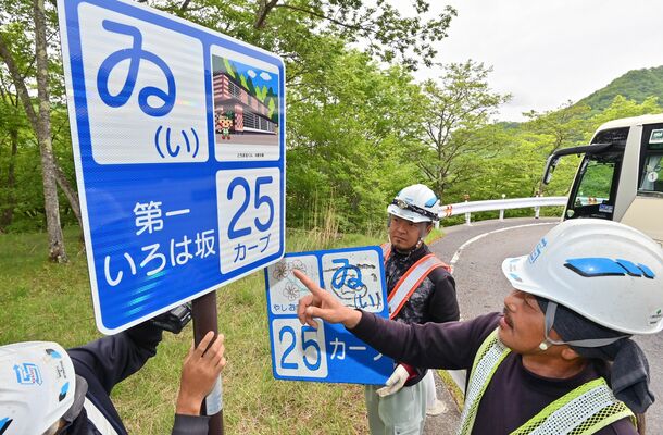 いろは坂のカーブ標識を新品にかけ替える作業員＝26日午前９時30分、日光市中宮祠