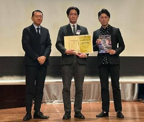 授賞式で表彰状を手にする早川社長（中央）＝１１日夜、横浜市