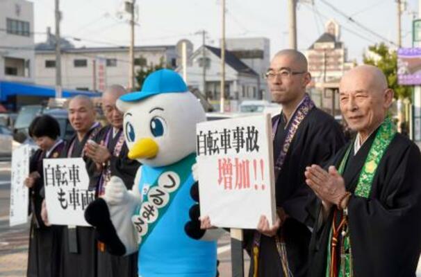 自転車の青切符制度の周知や交通ルールの順守を呼びかける僧侶ら=13日午後、大阪市鶴見区