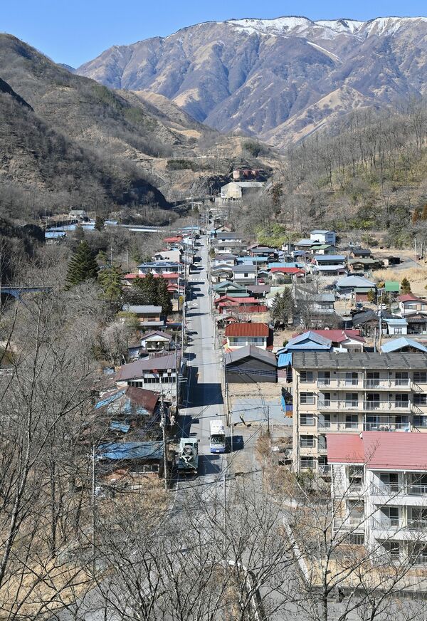 現在の日光市足尾地域北部の町並み。現在は煙害などで荒廃した山に木々が目立つようになった。中央奥に見えるのは製錬所跡＝27日午後１時30分、日光市足尾町上間藤