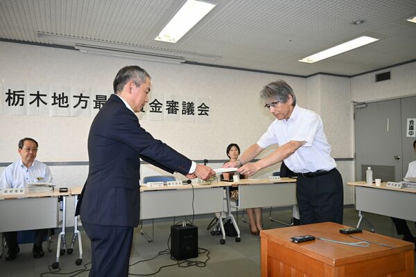 最低賃金改定の答申書を栃木労働局の川口秀人局長（左）に手渡す栃木地方最低賃金審議会の藤井亮二会長＝５日午後、宇都宮市