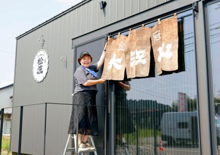 　松波酒造の新店舗に、崩壊した酒蔵から取り出したのれんを飾る金七聖子さん＝２０２５年８月、石川県能登町