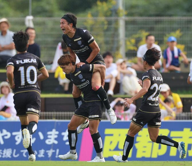 後半、チーム初ゴールを決めた栃木シティの森(中央)のもとに集まる選手ら=宮崎県新富町のいちご宮崎新富サッカー場