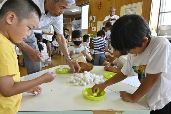 繭の周りについたけばを取る児童たち