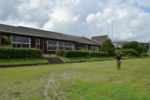 観光交流拠点としての活用へ向け改修する予定の旧長井小の校庭に立つ手塚さん