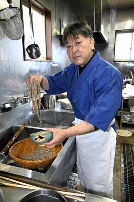 釜から引き上げたそばを丼に盛る磯さん＝那須塩原市