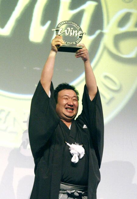 インターナショナル・ワイン・チャレンジのサケ部門で世界一称号の「チャンピオン」盾を突き上げる井上社長＝２０１０年９月、ロンドン