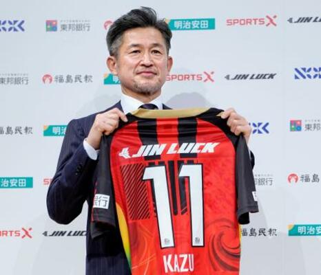 　Ｊ３福島への加入記者会見で、背番号「１１」のユニホームを手にする三浦知良＝９日、東京都内