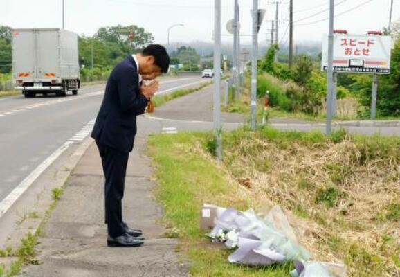 事故現場で献花し、手を合わせる「北都交通」の佐藤晃彦社長(手前)ら=18日午後、北海道八雲町