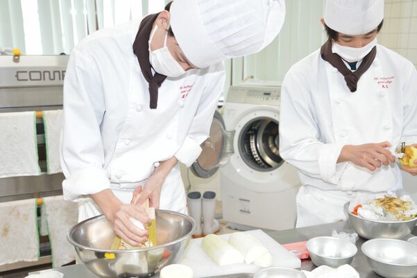 鬼おろしを使ってダイコンをすりおろす学生