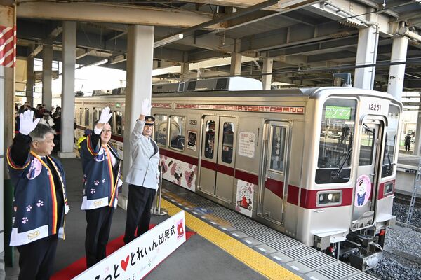 金子市長(中央)らの出発指示を受け、駅を発進する「さのまるっと♥とれいん」