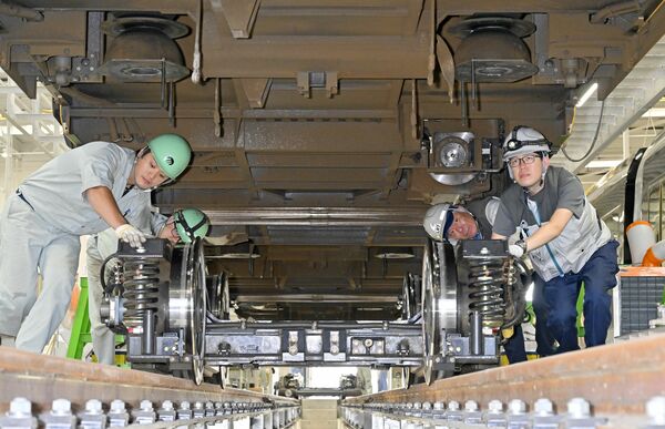 ＬＲＴの車体を上げ整備を終えた台車を運び入れる検修員ら＝28日午後２時20分、宇都宮市下平出町