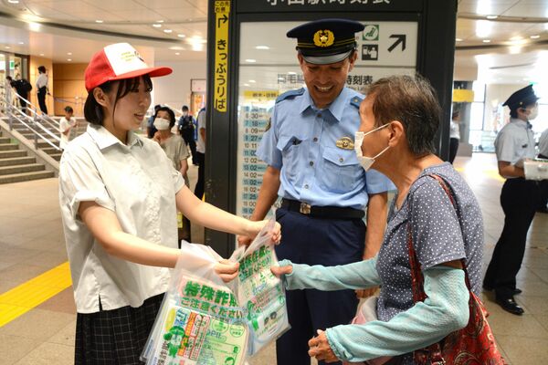 防犯を呼びかけるチラシなどを手渡す小山城南高の生徒（左）と黒嶋犯罪抑止対策官（中央）＝10日午前、ＪＲ小山駅